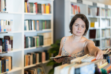 In bookstore woman choose book. New literature, bestseller, fantasy, drama, educational literature,...