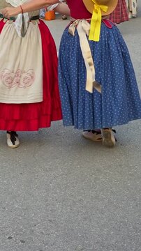 Low angle view of women in vibrant traditional blue and red skirts with straw hat and espadrilles performing a traditional folk dance at a cultural festival in Teulada, Spain. Dynamic movement of trad