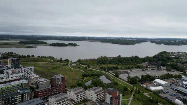 aerial drone video of Arabianranta in Helsinki, Finland, showing the sea, modern residential buildings, green spaces, and the peaceful Nordic urban landscape during summer.