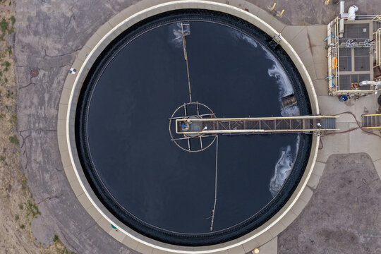 Aerial view of Salt Lake City Water Reclamation Facility Main Plant featuring a large circular clarifier tank with a central rotating bridge and dark water Salt Lake City, Utah, United States.