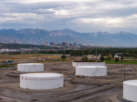 Aerial view of petroleum storage tanks in an industrial area with the Salt Lake City skyline and Wasatch Mountains in the background South Salt Lake, Utah, United States.