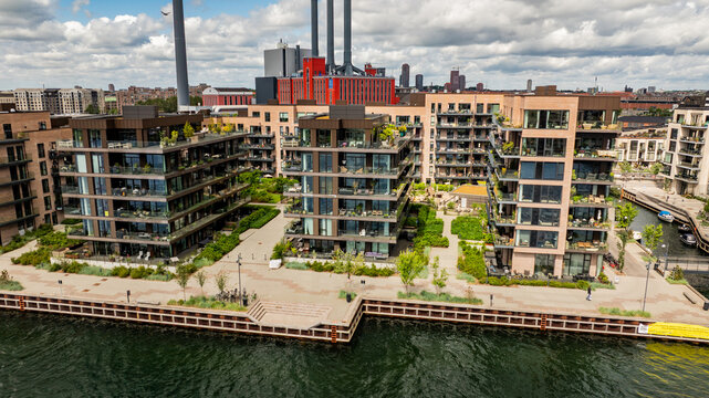 Aerial view of modern residential apartment buildings with balconies and green spaces along the canal in Copenhagen, Denmark.
