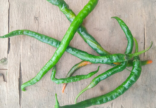 top view of fresh green chili peppers on rustic wooden background