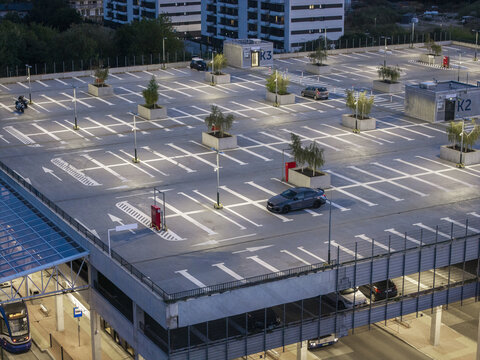 Aerial view of a modern park and ride facility with marked parking spaces, small trees in planters, and a car on the top level in Krakow, Lesser Poland Voivode, Poland.