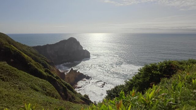 光に照らされた海と断崖の岬を望む風景。