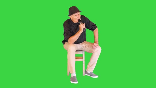 Professional mature musician sings a serious song into the microphone on a Green Screen, Chroma Key.