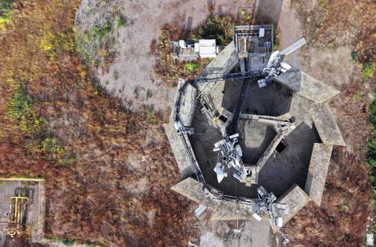 Aerial view of antenna signal repeater inside a hexagonal concrete structure surrounded by dry vegetation in Pancevo, Vojvodina, Serbia.