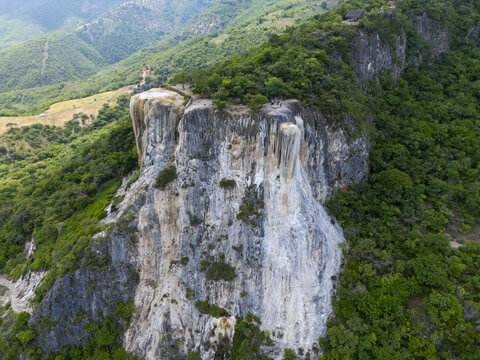 Aerial view of the petrified waterfalls at Hierve el Agua surrounded by lush green mountains and rocky cliffs in Oaxaca de Juarez, Oaxaca, Mexico.