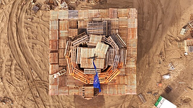Aerial view of the Vreugdevuur Scheveningen bonfire structure made of wooden pallets on the sandy Noorderstrand beach in Den Haag, Zuid-Holland, Netherlands.