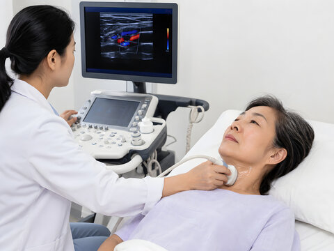 Medical sonographer performing carotid Doppler ultrasound on older Asian woman