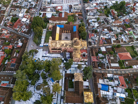 Aerial view of the historic Templo de Santo Domingo de Guzman surrounded by colonial rooftops, trees, and narrow streets at sunrise in San Cristobal de las Casas, Chiapas, Mexico.