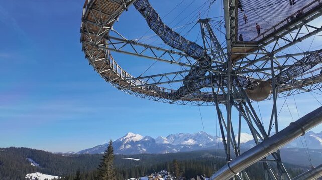 Male Ciche, Poland, SkyWalk Serce Poronina observation deck and elevated walkway above forested slopes with snowy Tatra Mountains on a sunny winter day.