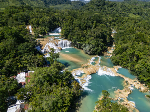 Aerial view of the turquoise waterfalls of Cascadas de Agua Azul surrounded by lush tropical jungle and limestone formations in Agua Azul, Chiapas, Mexico.