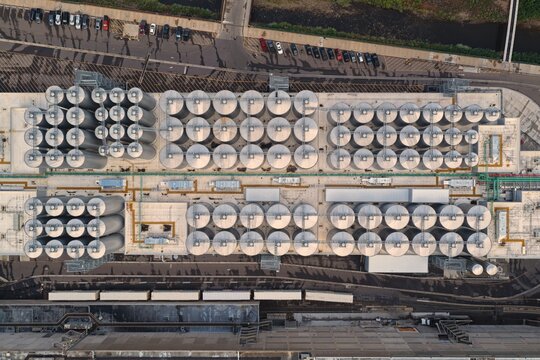 Aerial view of Coors Brewery featuring rows of large industrial fermentation tanks and metal silos in a complex facility with parking and railway tracks in Golden, Colorado, United States.