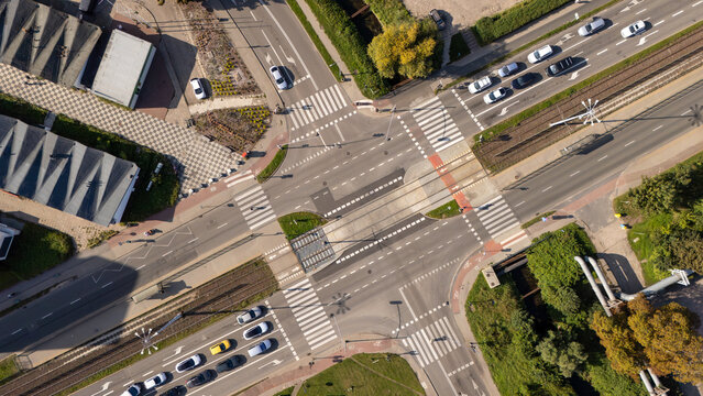 Aerial view of a busy urban intersection with tram tracks, pedestrian crossings, and vehicles on asphalt roads in Gdansk, Poland.