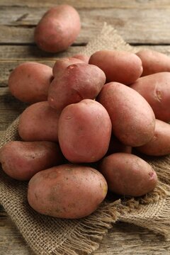 Many ripe red potatoes on wooden table, closeup