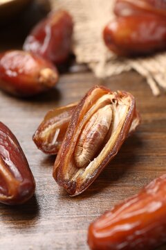 Whole and cut dried dates on wooden table, closeup