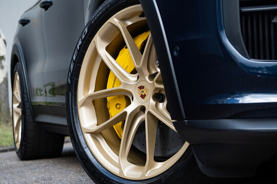 Close-Up of Gold Alloy Wheel and Yellow Brake Caliper on Dark Blue Porsche Cayenne SUV