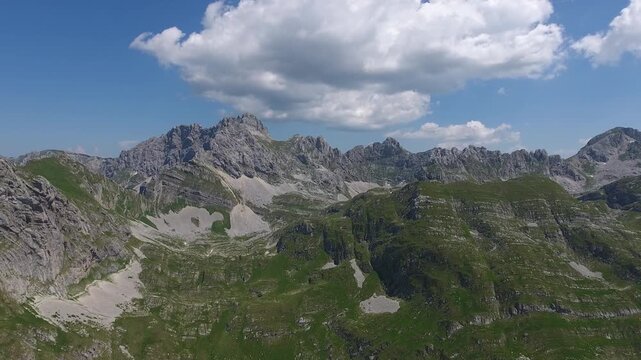 Aerial view of the rugged peaks of Bobotov Kuk in the Durmitor National Park, surrounded by green slopes and rocky terrain in Zabljak Municipality, Montenegro.