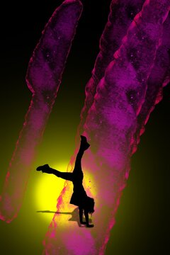 Silhouette of a b-girl performing a handstand on stage with vibrant neon lighting background