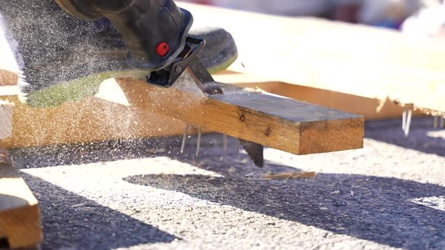 Close up of a power tool cutting through a wooden plank creating sawdust at a construction site