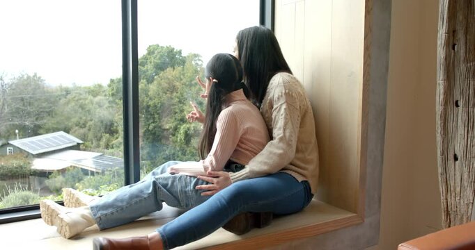 Mother and Indian tween daughter on bench pointing at solar panels and sharing view, copy space