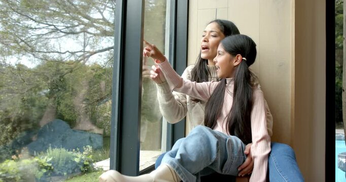 Mother and daughter exploring garden, following pointing, hugging and tracing tree through window