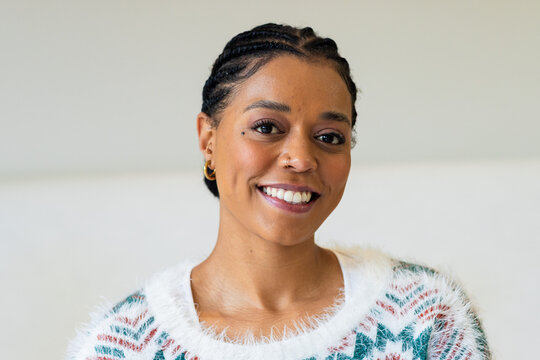 African American woman smiling warmly while wearing fuzzy knit sweater in studio corner