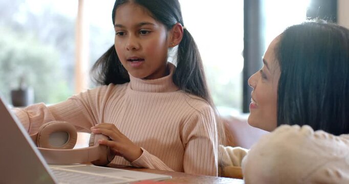 Woman pointing laptop screen triggers Indian girl reaching earcup listening for help at table