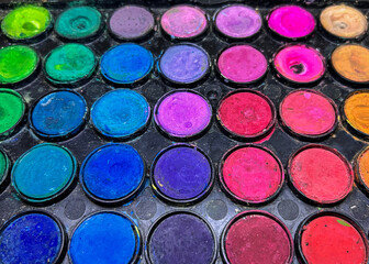Fototapeta premium Vibrant round watercolor paint palette vector illustration, colorful makeup or face paint compact with bright multi-colored circular pans including green, blue, purple, pink, and orange in a black tra