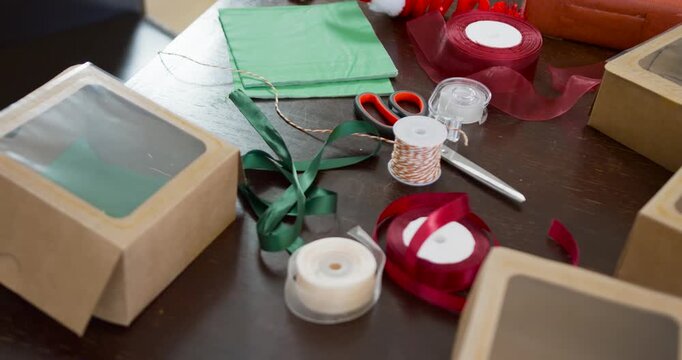 Camera is pulling back and revealing Christmas wrapping supplies on wooden table for display