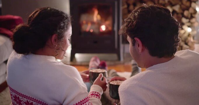 African American couple sitting at home by stove woman turning starting Christmas chat sipping mugs