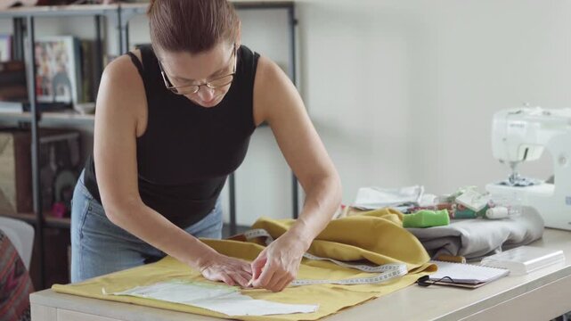 Middle aged woman tailor precisely sewing clothing patterns in small business fashion studio independent entrepreneur business owner concept 4K footage.Middle aged woman tailor precisely sewing clothi