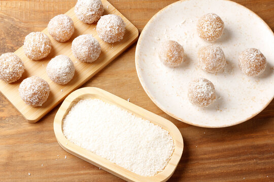 Brazilian coconut beijinho on a wooden board and a plate. A traditional sweet for parties and celebrations