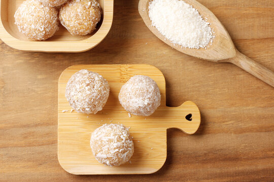 Brazilian coconut beijinho on a bamboo board atop a rustic wooden table. Traditional confectionery for parties and celebrations.