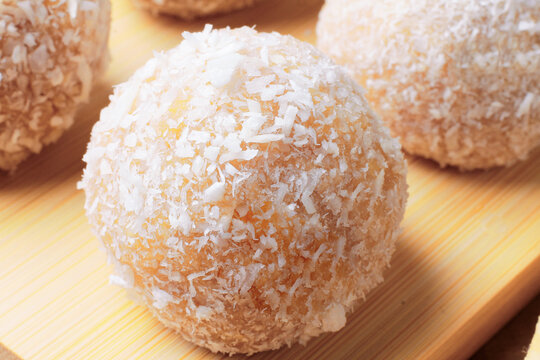 Traditional Brazilian beijinho coated in shredded coconut, resting on a bamboo surface. A dessert for parties and birthdays.