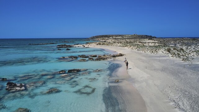 A person walks on the sandy, rocky shore along the clear blue sea. Quiet and unspoilt nature, Elafonissi, lagoon, south-western tip of Crete, Crete, Greek islands, Greece