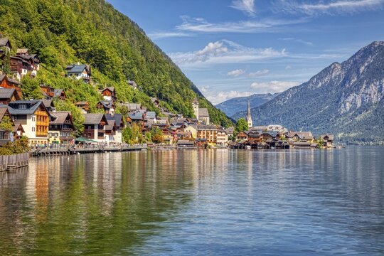 A, Hallstatt, hdr, A picturesque lakeside village with colorful houses against a mountain backdrop under a blue sky, Austria