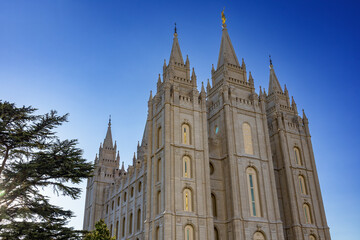Fototapeta premium Salt Lake Temple at sunset, beautifully illuminated against a colorful evening sky, showcasing the iconic granite architecture, distinctive towers, and peaceful grounds of this historic Latter-day Sai