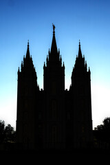 Fototapeta premium Salt Lake Temple at sunset, beautifully illuminated against a colorful evening sky, showcasing the iconic granite architecture, distinctive towers, and peaceful grounds of this historic Latter-day Sai