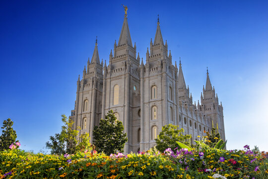 Salt Lake Temple at sunset, beautifully illuminated against a colorful evening sky, showcasing the iconic granite architecture, distinctive towers, and peaceful grounds of this historic Latter-day Sai