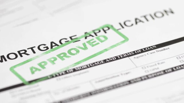 Close up of a paper mortgage application form with a green approved rubber stamp.