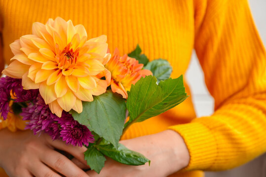 Woman showing into camera yellow dahlia Autumn garden colorful flowers. Beautiful autumnal bouquet dahlia chrysanthemum. Red pink orange fall color fall floral background. Flower shop and florist