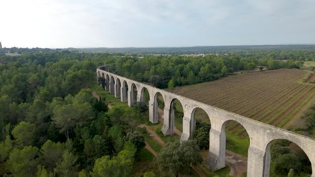 Long historic stone aqueduct bordering woodland and cultivated farmland, aerial