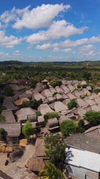 Sade Village shows traditional Sasak houses and thatched rooftops across rural Lombok in a vertical right-orbit drone shot.