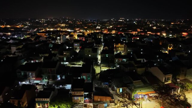 Aerial view of Hoi An urban landscape at night, highlighting illuminated streets and rooftops, creating a vibrant city atmosphere