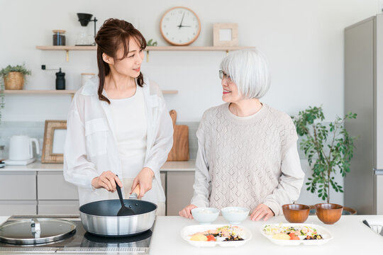 The smiles of a mother and daughter enjoying cooking together in the kitchen.