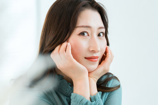 頬に触れて微笑む女性,美肌に満足するスキンケアと美容イメージ