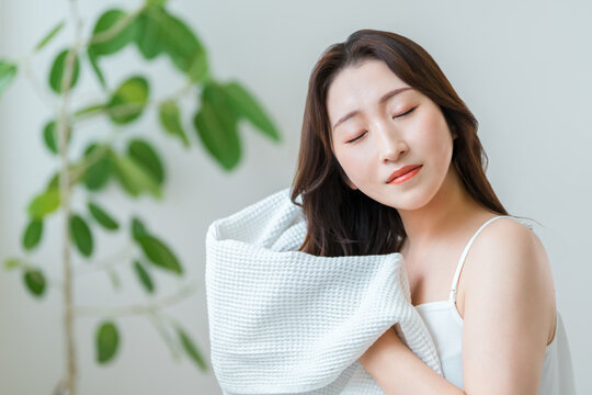 A woman in her 40s towel-dries her hair after washing it; hair care routine.