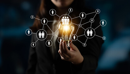 A businesswoman holds a light bulb symbolizing innovative ideas within a network of connections, showcasing collaboration and modern technology in a professional environment. Ledger